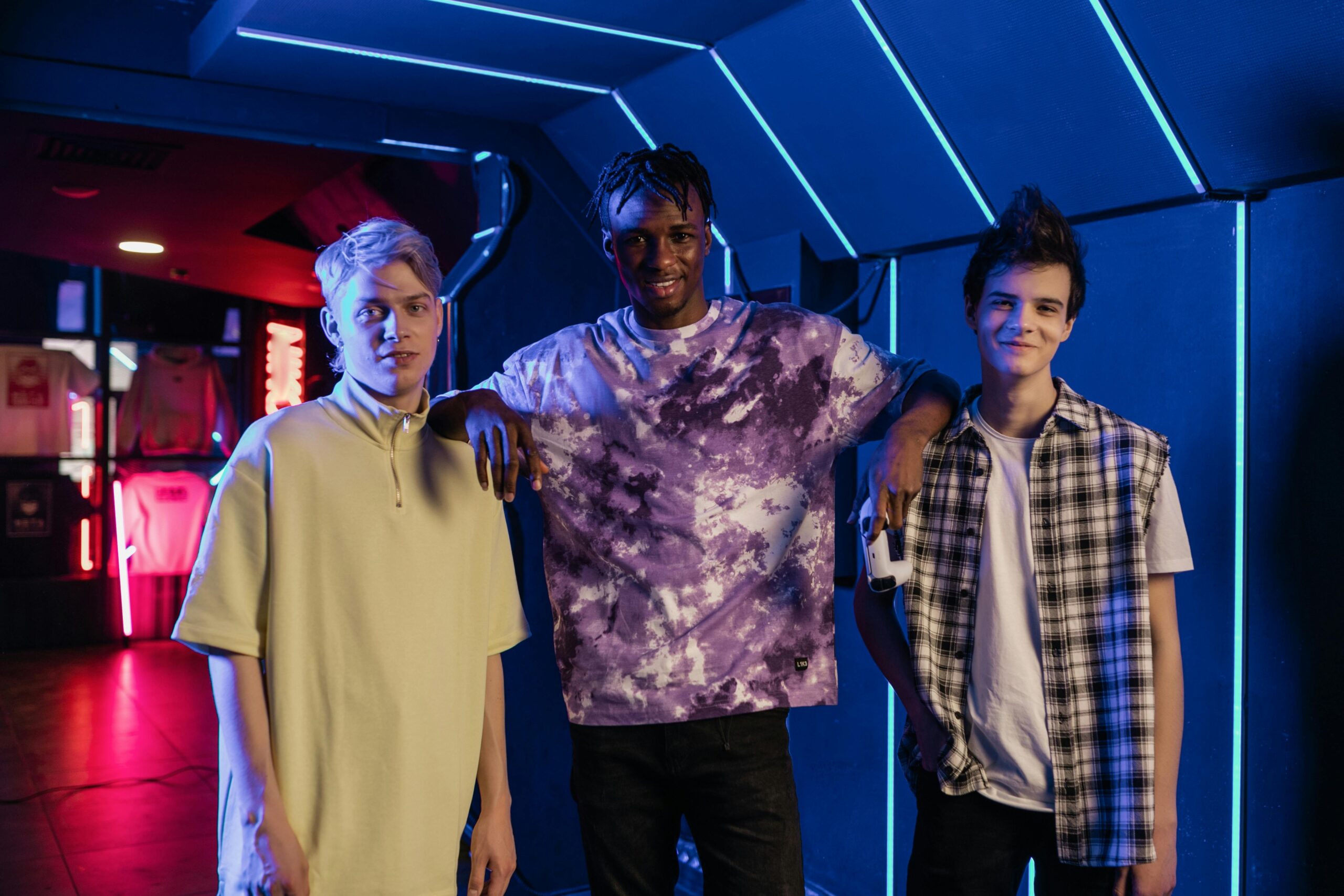 Three friends pose cheerfully in a neon-lit room, exuding warmth and connection.